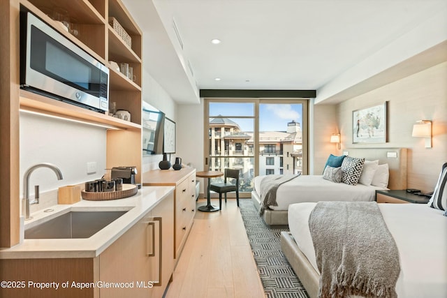 bedroom featuring access to exterior, sink, and light hardwood / wood-style floors