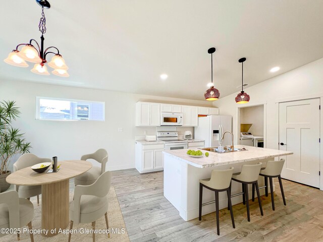 1652 E 17th Cir, Rifle, CO 81650 - kitchen with white appliances, separate washer and dryer, light wood-style flooring, a center island with sink, and a chandelier