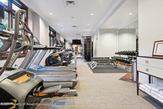 exercise room with carpet floors and ornamental molding