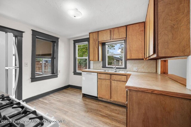 580 Curtis Ave, De Beque, CO 81630 - kitchen featuring white appliances, light countertops, a sink, light wood-style flooring, and tasteful backsplash