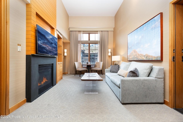 living room with carpet flooring, a fireplace, and a towering ceiling