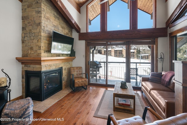 living area with high vaulted ceiling, a fireplace, and hardwood / wood-style flooring