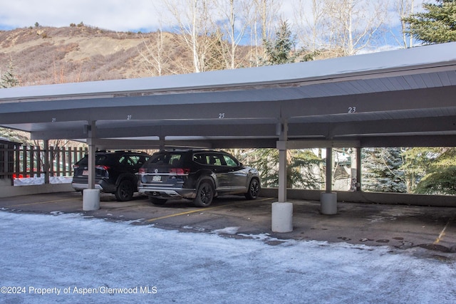 view of vehicle parking featuring a mountain view and a carport