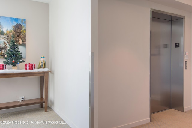 hallway featuring light carpet and elevator