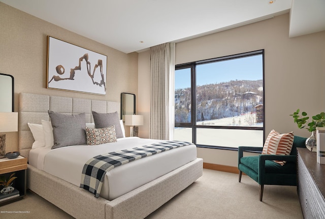 bedroom with a mountain view, light carpet, and multiple windows