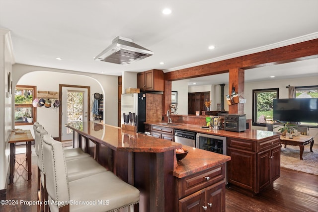 kitchen with appliances with stainless steel finishes, beverage cooler, a center island, dark hardwood / wood-style floors, and range hood