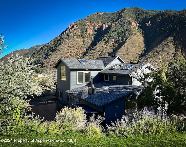 back of property with a deck with mountain view