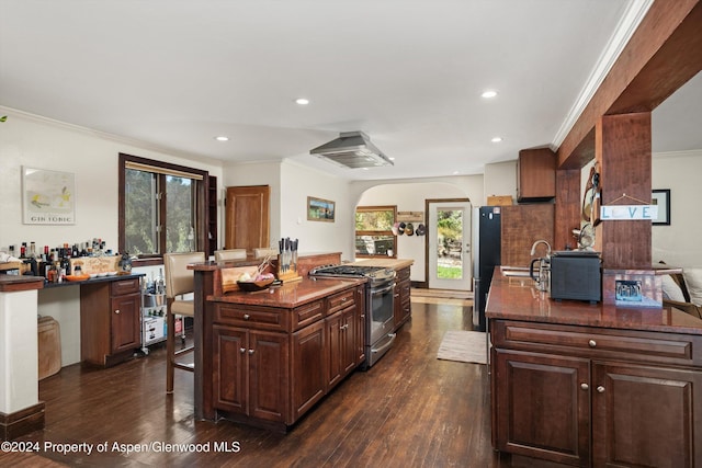 kitchen with a kitchen island with sink, crown molding, stainless steel appliances, and dark hardwood / wood-style floors