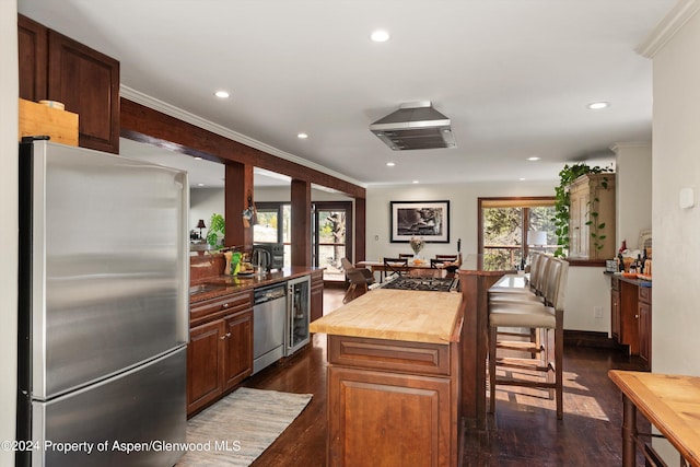 kitchen with ornamental molding, stainless steel appliances, butcher block countertops, a kitchen island, and dark hardwood / wood-style floors