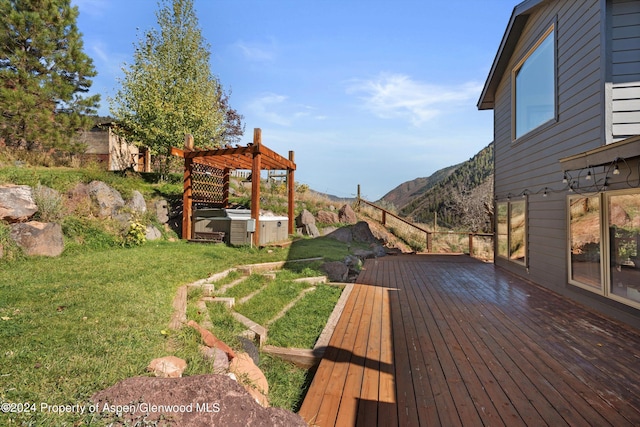 deck featuring a lawn, a mountain view, a pergola, and a hot tub