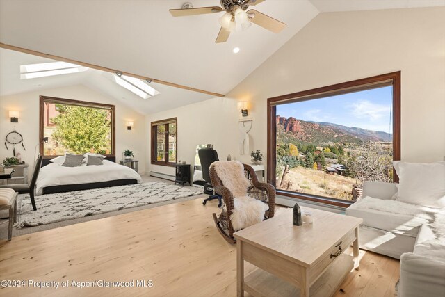 bedroom featuring a skylight, a mountain view, ceiling fan, and multiple windows