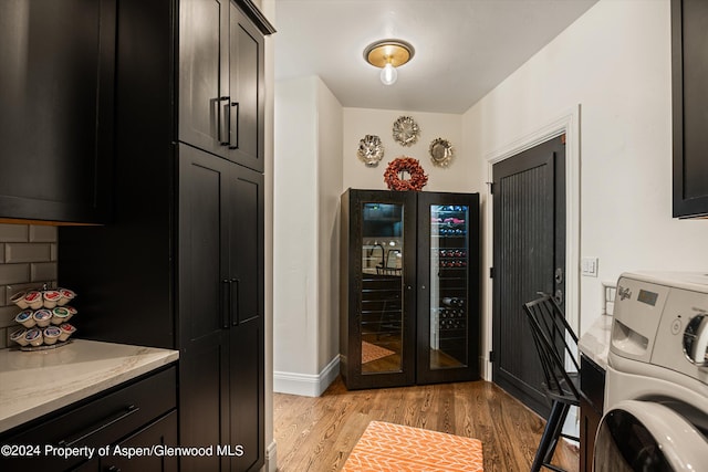 washroom featuring washer / clothes dryer, light hardwood / wood-style flooring, and cabinets