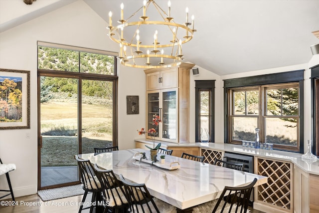 dining area featuring light hardwood / wood-style floors, lofted ceiling, wine cooler, and an inviting chandelier