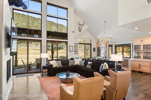 living room featuring hardwood / wood-style flooring, high vaulted ceiling, and a chandelier