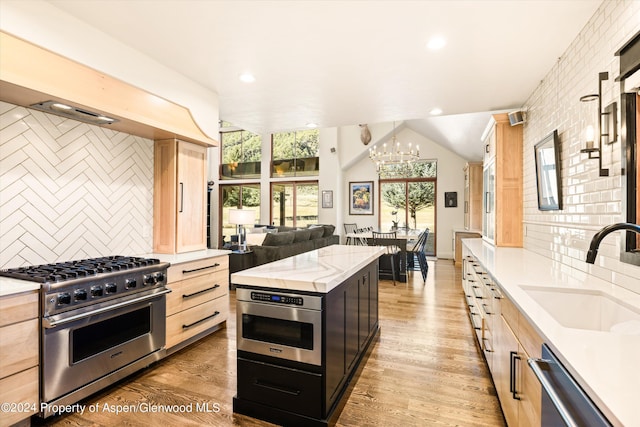 kitchen featuring backsplash, stainless steel appliances, sink, light brown cabinets, and a notable chandelier