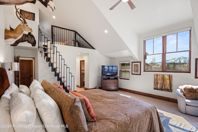 carpeted bedroom with ceiling fan and high vaulted ceiling