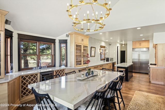 dining area featuring light hardwood / wood-style flooring, beverage cooler, vaulted ceiling, and an inviting chandelier