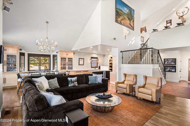 living room with hardwood / wood-style flooring, high vaulted ceiling, and an inviting chandelier