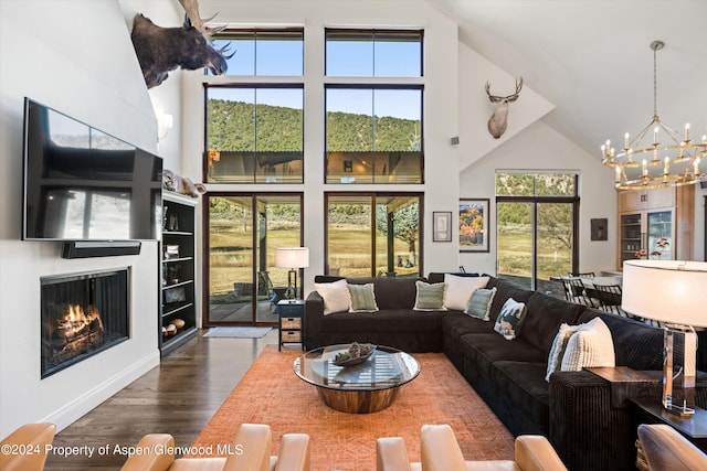 living room featuring dark hardwood / wood-style flooring, high vaulted ceiling, built in features, and an inviting chandelier