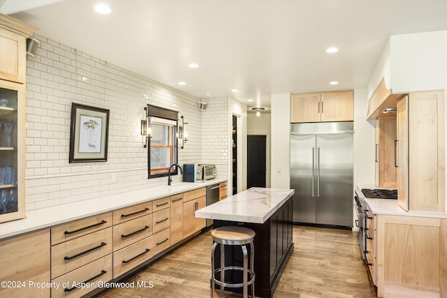 kitchen with a kitchen breakfast bar, tasteful backsplash, premium appliances, light brown cabinets, and a kitchen island