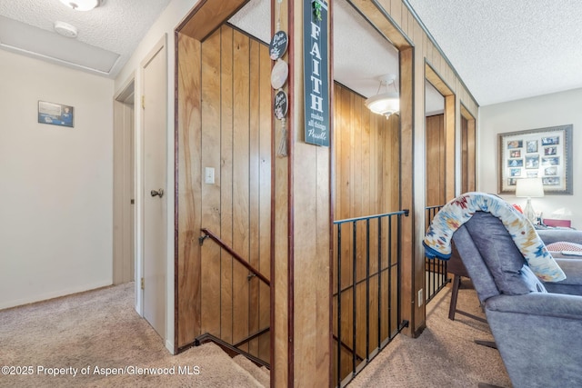 2201/2203 B St, Craig, CO 81625 - hall featuring carpet flooring, a textured ceiling, an upstairs landing, and wood walls