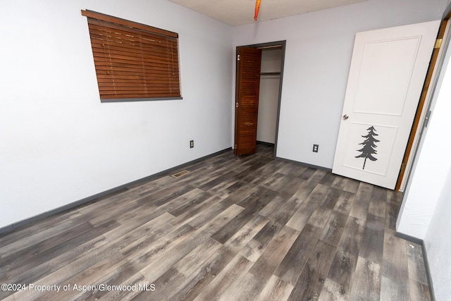 unfurnished bedroom with dark hardwood / wood-style floors and a closet