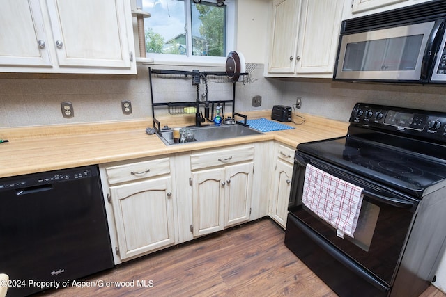 kitchen featuring decorative backsplash, dark hardwood / wood-style flooring, sink, and black appliances