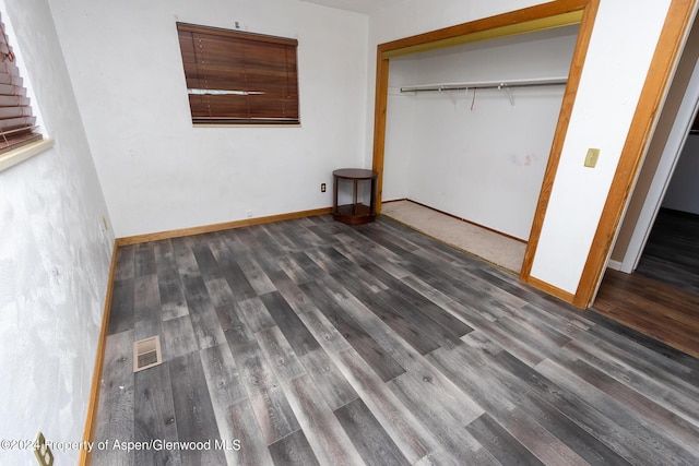 unfurnished bedroom with dark hardwood / wood-style flooring and a closet