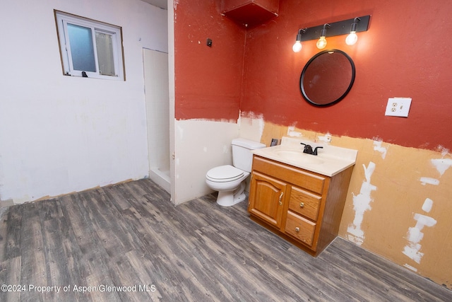 bathroom with a shower, toilet, vanity, and hardwood / wood-style flooring