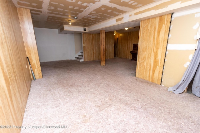 basement featuring carpet and wood walls