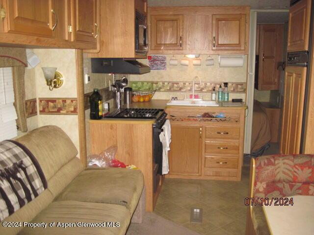 kitchen featuring exhaust hood, sink, tile patterned flooring, decorative backsplash, and high end stove