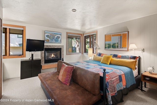 bedroom featuring a tile fireplace, a textured ceiling, and carpet flooring