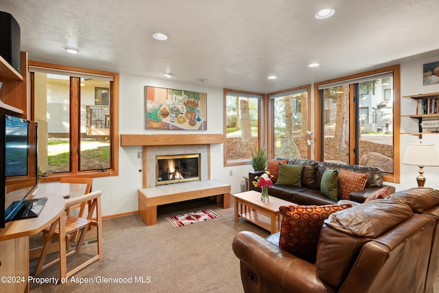 living room with carpet flooring, a textured ceiling, a wealth of natural light, and a fireplace