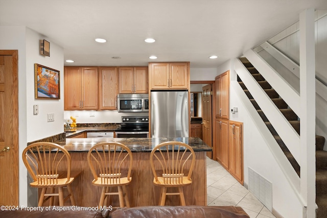 kitchen featuring kitchen peninsula, a kitchen breakfast bar, stainless steel appliances, and light tile patterned flooring