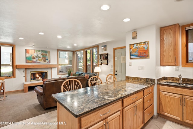 kitchen featuring kitchen peninsula, sink, light tile patterned floors, and dark stone counters