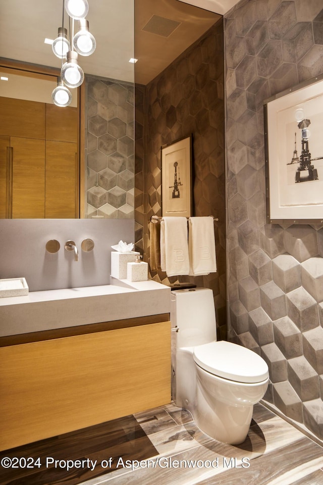 bathroom featuring wood-type flooring, vanity, toilet, and tile walls