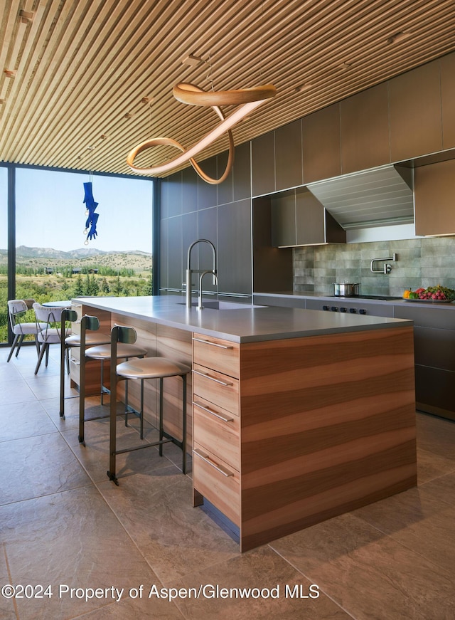 kitchen featuring decorative backsplash, sink, wooden ceiling, a mountain view, and a breakfast bar area