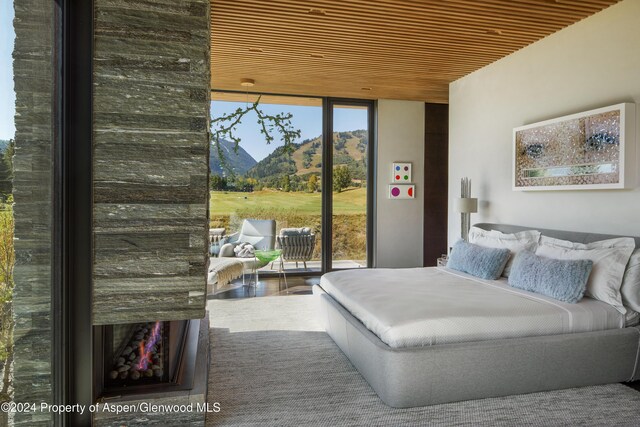 bedroom featuring a mountain view, access to exterior, wooden ceiling, and multiple windows