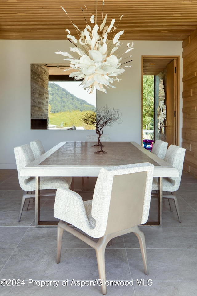 dining room with tile patterned flooring, a mountain view, wood walls, and wooden ceiling