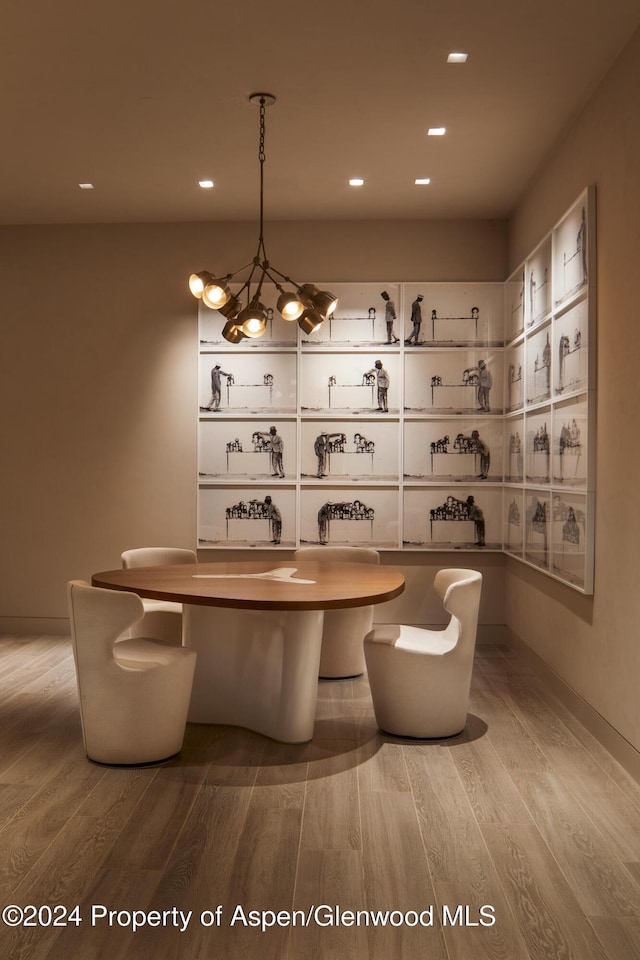 bar featuring light hardwood / wood-style floors, white cabinetry, hanging light fixtures, and a notable chandelier