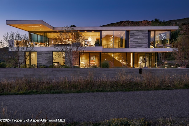 back house at dusk featuring a balcony