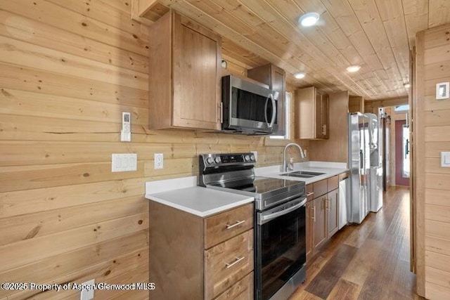 kitchen featuring appliances with stainless steel finishes, dark hardwood / wood-style floors, wooden walls, sink, and wooden ceiling