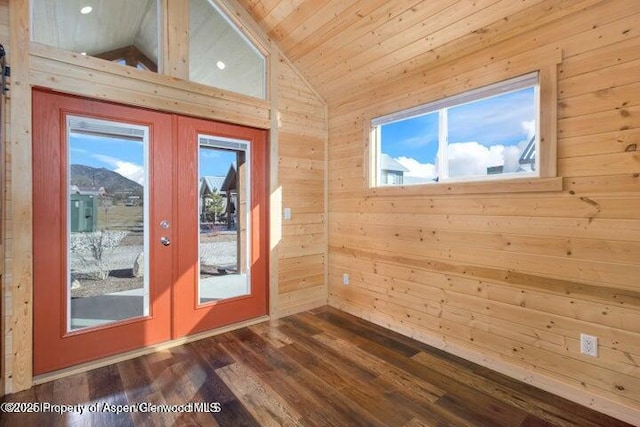 entryway with vaulted ceiling, french doors, a healthy amount of sunlight, and wood walls