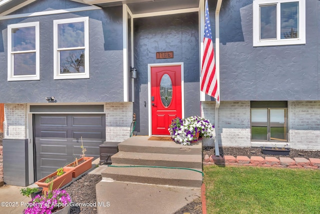 1186 Washington St, Craig, CO 81625 - view of exterior entry with an attached garage, stucco siding, and brick siding