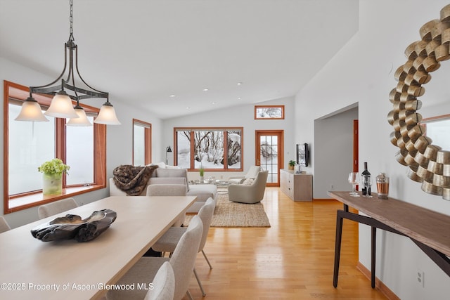 dining space featuring light hardwood / wood-style floors, vaulted ceiling, and plenty of natural light