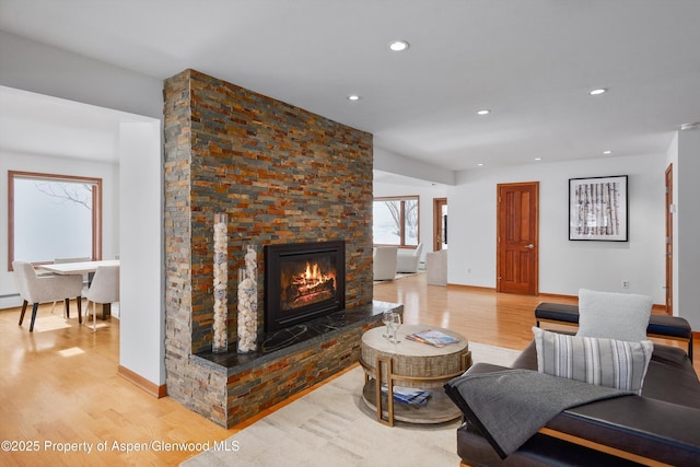 living room featuring light hardwood / wood-style floors and a stone fireplace