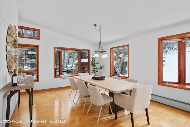 dining room with light hardwood / wood-style floors, a baseboard heating unit, and lofted ceiling