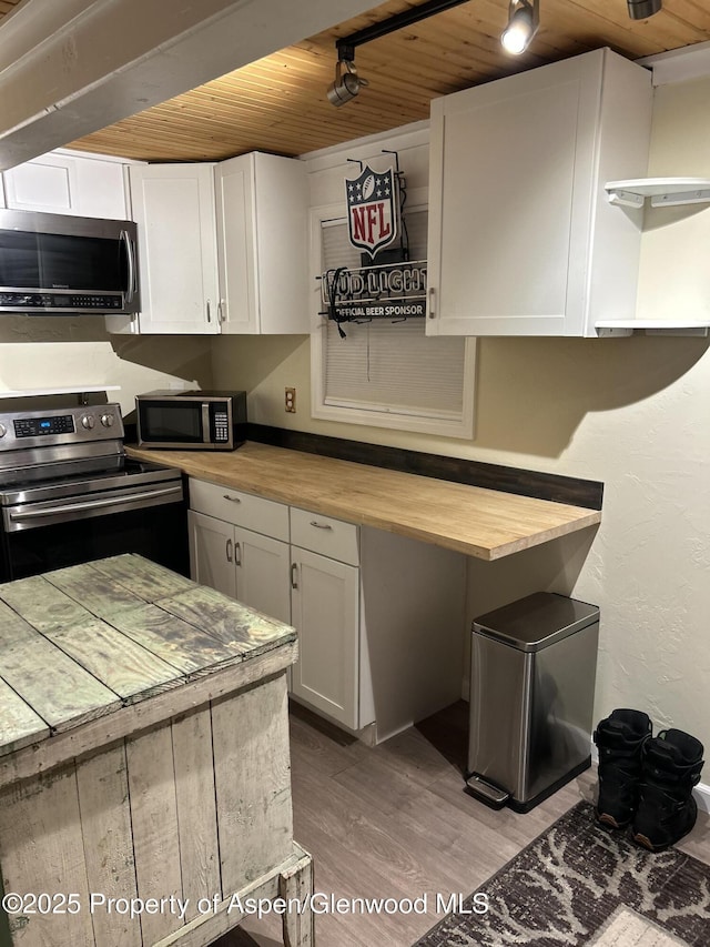 kitchen with wooden counters, appliances with stainless steel finishes, light hardwood / wood-style floors, white cabinetry, and wood ceiling