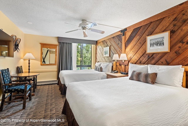 300 Carriage Way Unit 506, Snowmass Village, CO 81615 - bedroom featuring a baseboard radiator, a textured ceiling, wooden walls, carpet, and a ceiling fan