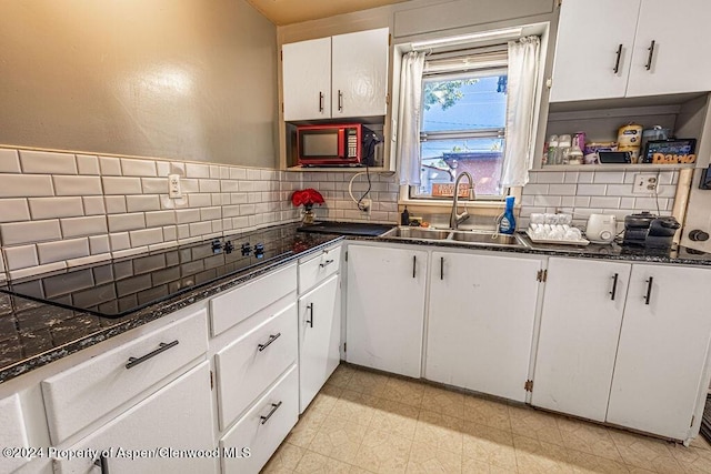 kitchen with backsplash, black appliances, sink, dark stone countertops, and white cabinetry